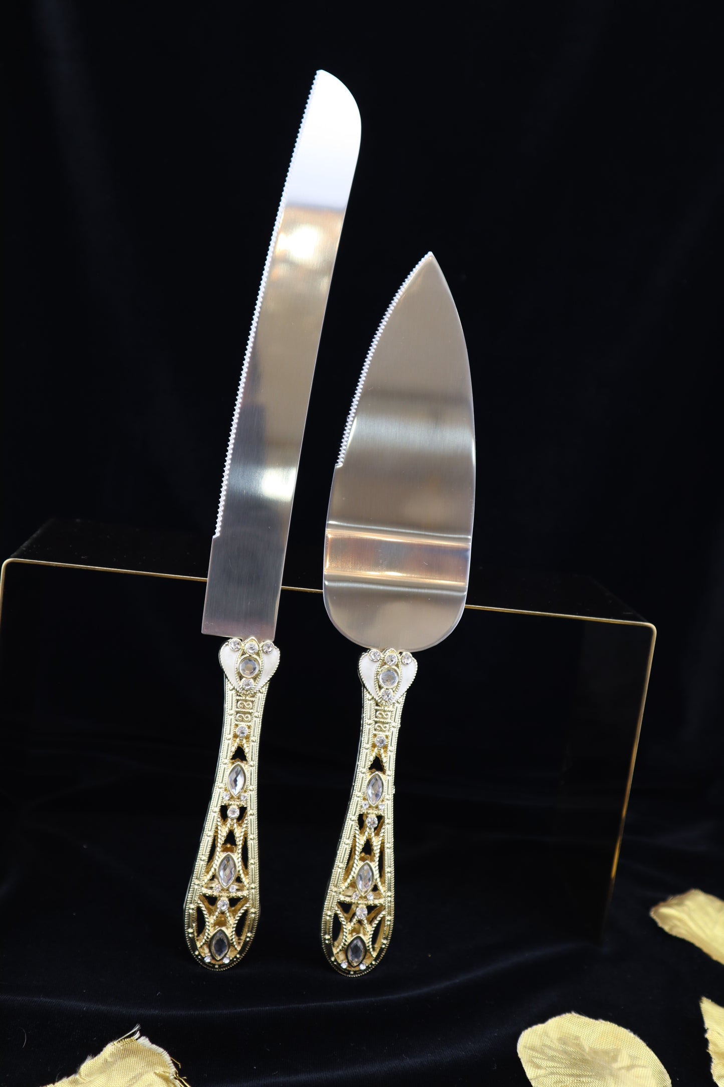 Silver cake server set with gold embellishments on a black background