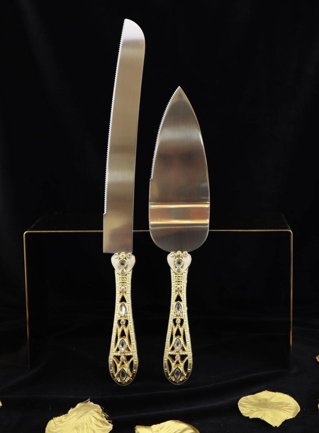 Gold cake server set on a black background with gold leaf decorations