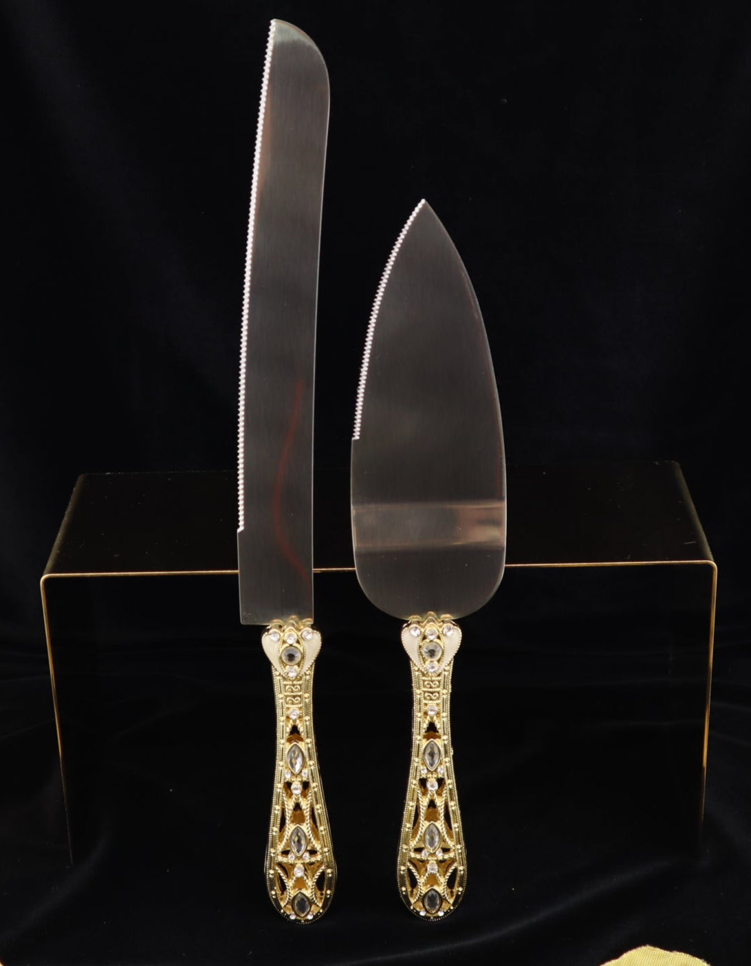Gold-handled cake knife and server set on a black background