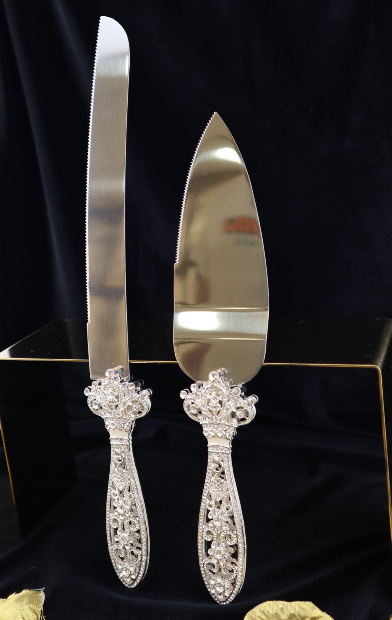 Silver cake server and knife set with decorative handles on a black fabric background