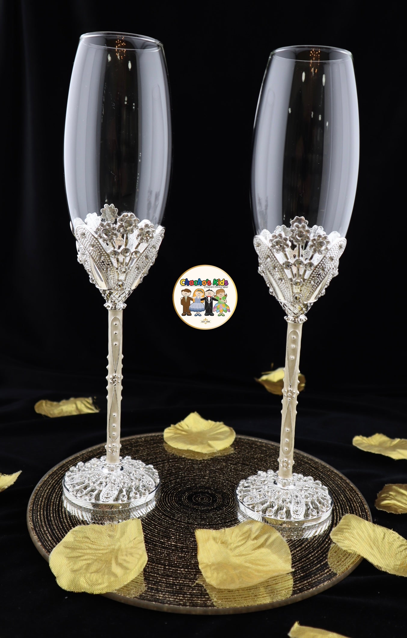 Two ornate Wedding champagne flutes on a black surface with gold leaves.