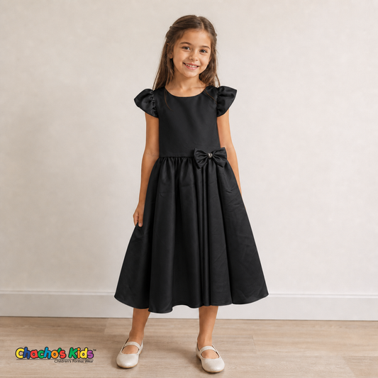 Girl wearing black satin flower girl dress with bow, flutter sleeves and full skirt