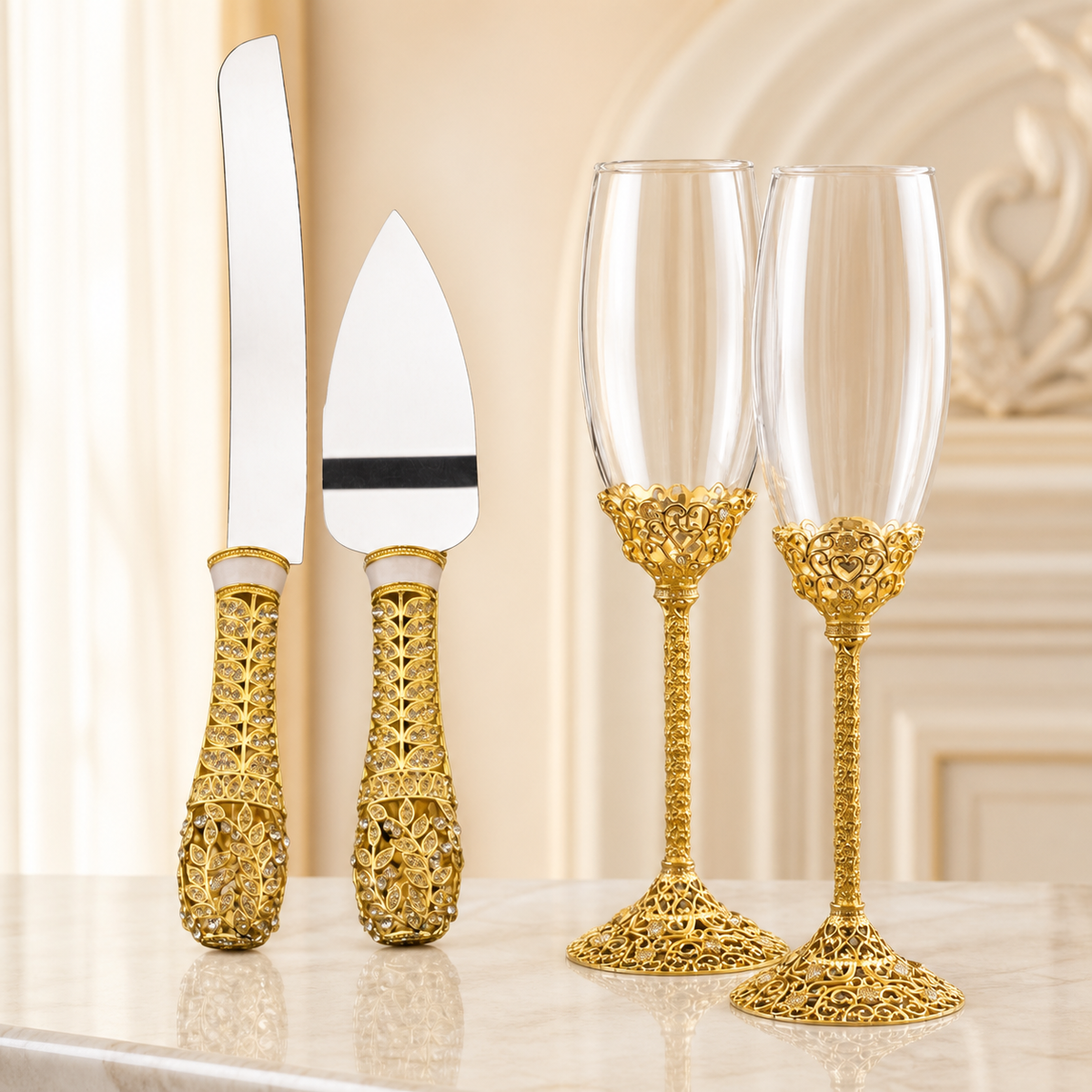 Gold wedding cake knife, server, and matching champagne flutes displayed in an elegant cream interior