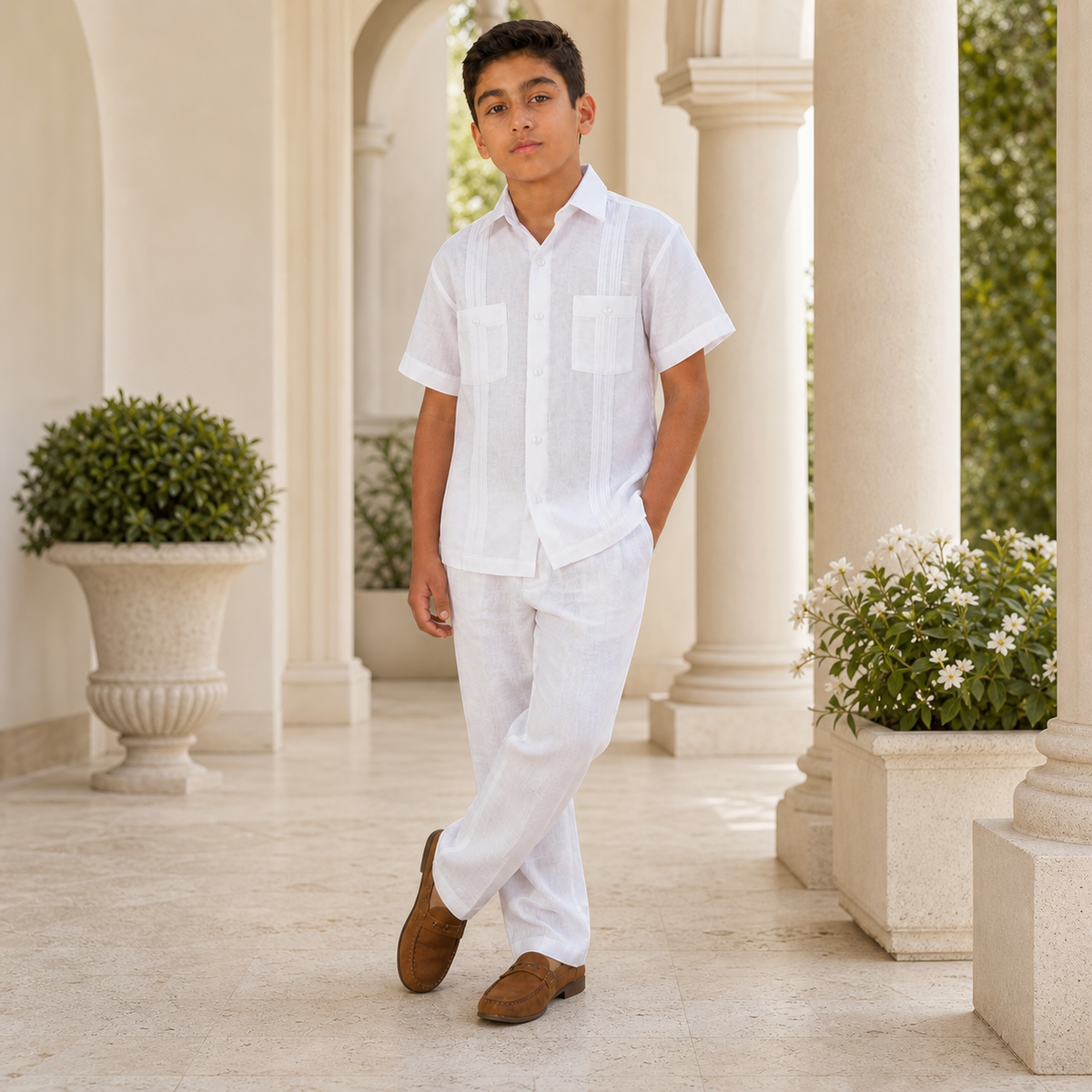 Boy wearing a white linen guayabera shirt and matching pants on an elegant cream veranda