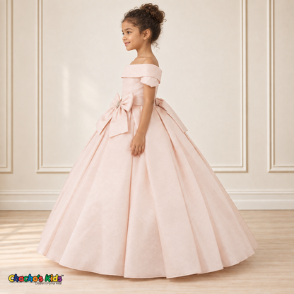 Blush ball gown dress, style 9177, left-facing side view on a child model with a folded neckline, jeweled waist bow and full floor-length skirt.