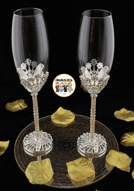 Two crystal-studded Wedding champagne flutes on a decorative stand with gold leaves and a logo in the corner.