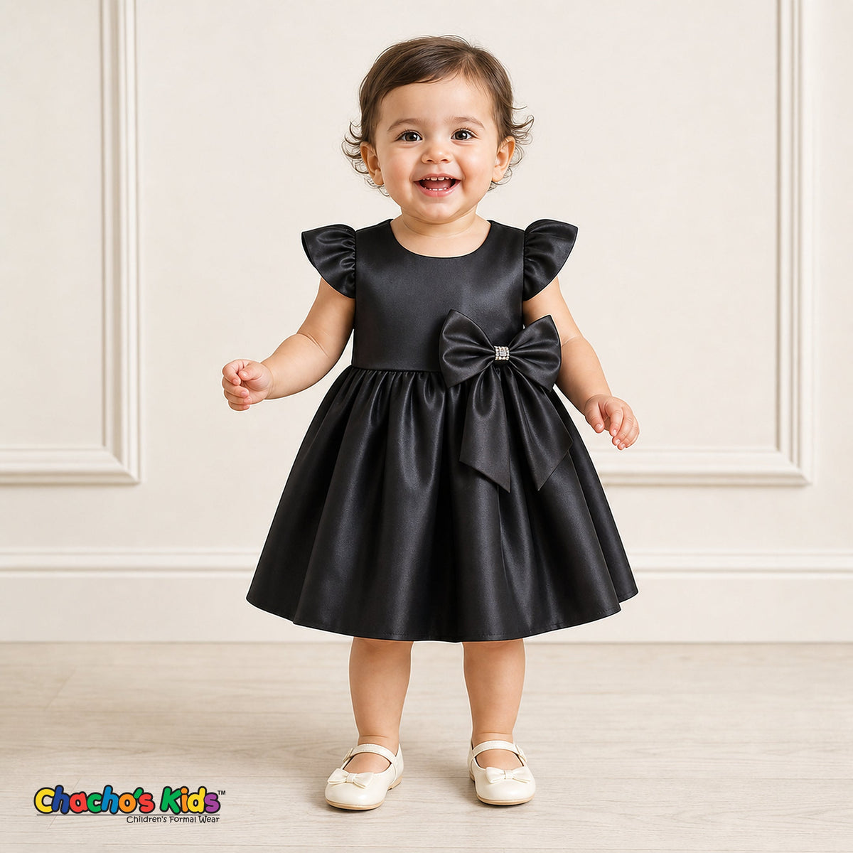 Baby girl wearing black satin flower girl dress with flutter sleeves and bow, style B263