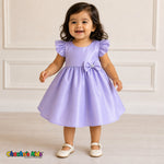 Baby girl wearing lilac satin flower girl dress with flutter sleeves and bow, style B263