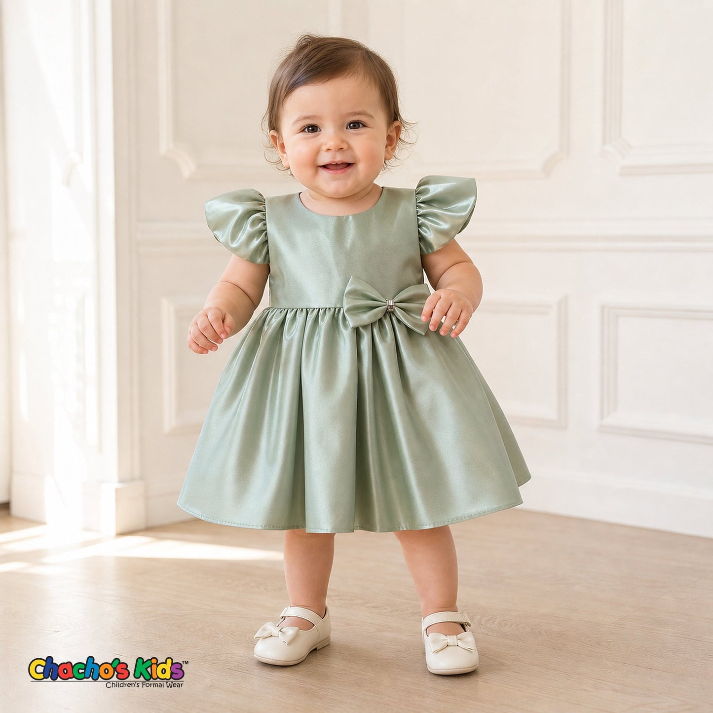 Baby girl wearing sage green satin flower girl dress with flutter sleeves and bow, style B263