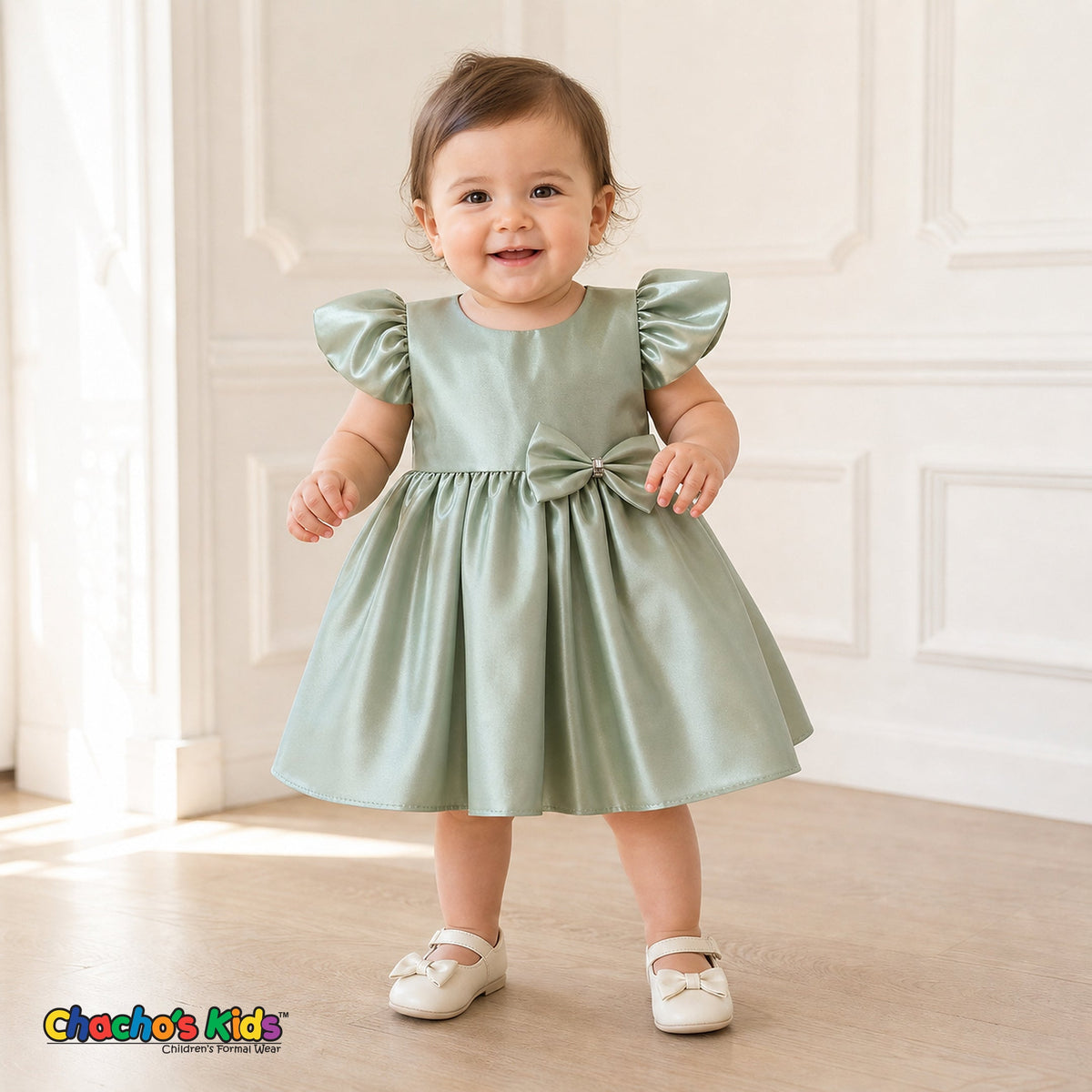 Baby girl wearing sage green satin flower girl dress with flutter sleeves and bow, style B263