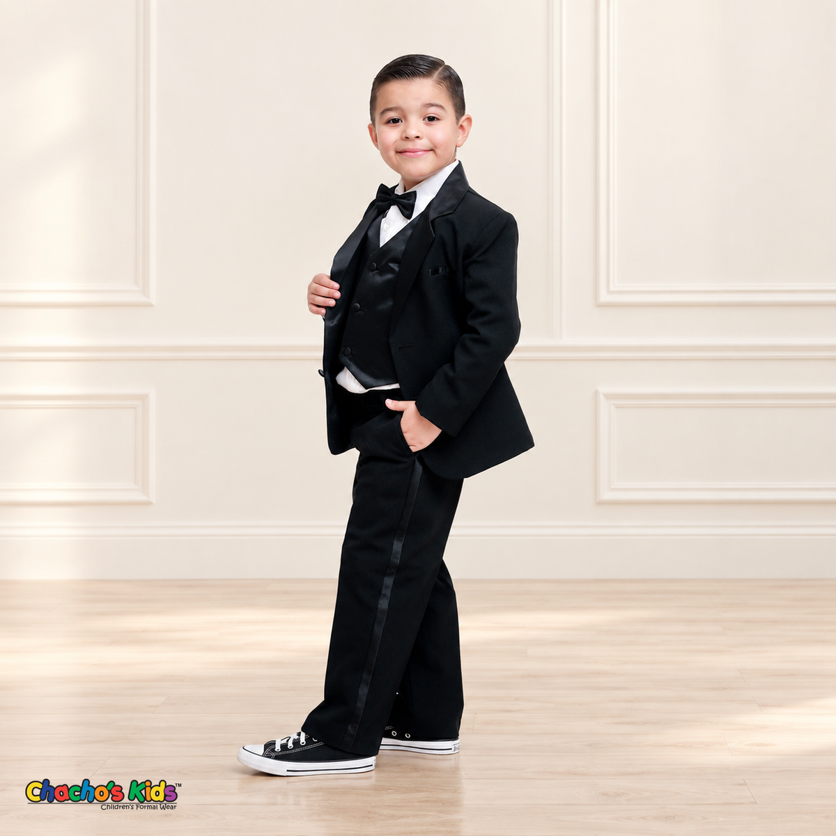 Boys Signature Tuxedo in Black (BY010), child model full-length three-quarter view with satin vest, black bow tie and trouser stripe.