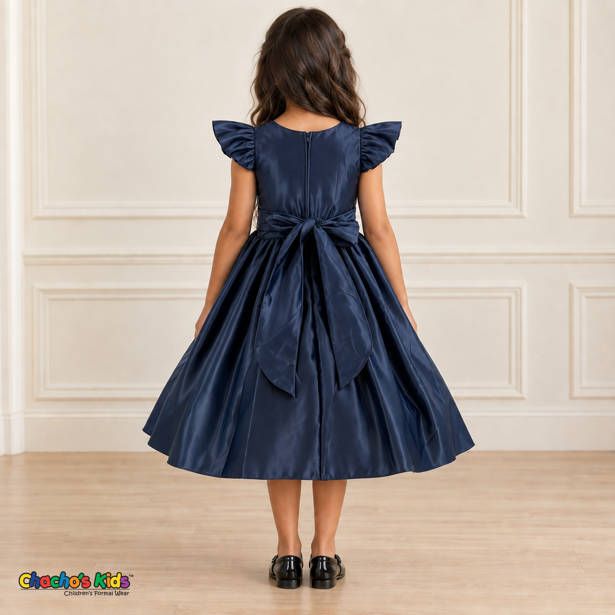 Back view of a girl wearing the navy blue satin flower girl dress, Style 263, showing flutter sleeves, a center-back zipper and a large sash bow with long tails.