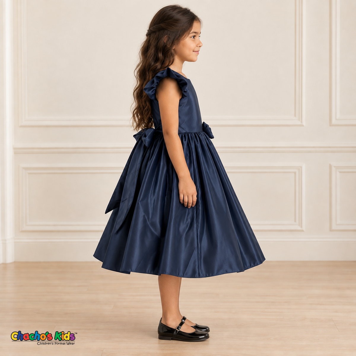 Side view of a girl wearing the navy blue satin flower girl dress, Style 263, showing flutter sleeves, the matching back sash bow and the full gathered skirt.