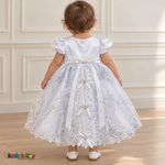 Baby girl wearing the white Virgin Mary Baptism Dress, Style 374, back without cape, showing the satin sash, floral embroidery and ribbon bows.