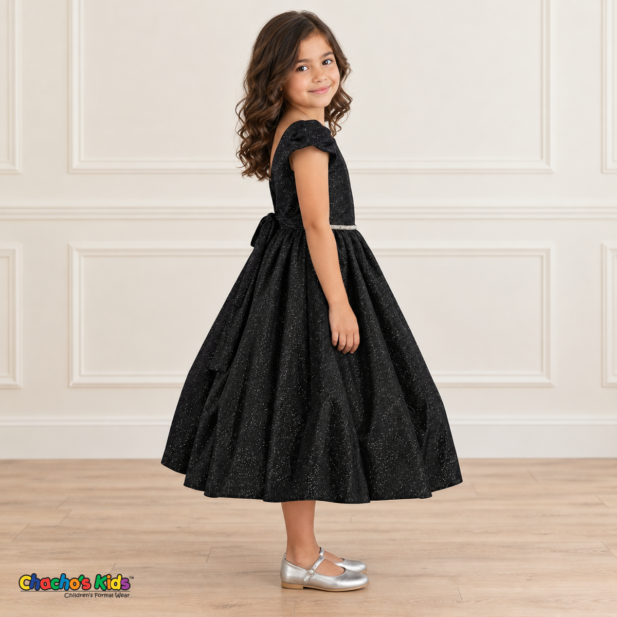 Side view of a girl wearing the black shimmer puff sleeve party dress, Style 444, showing the gathered skirt and matching back sash.