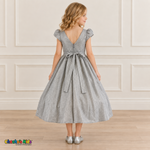 Back view of a girl wearing the silver shimmer puff sleeve party dress, Style 444, showing the V-shaped back, zipper and tied sash bow.