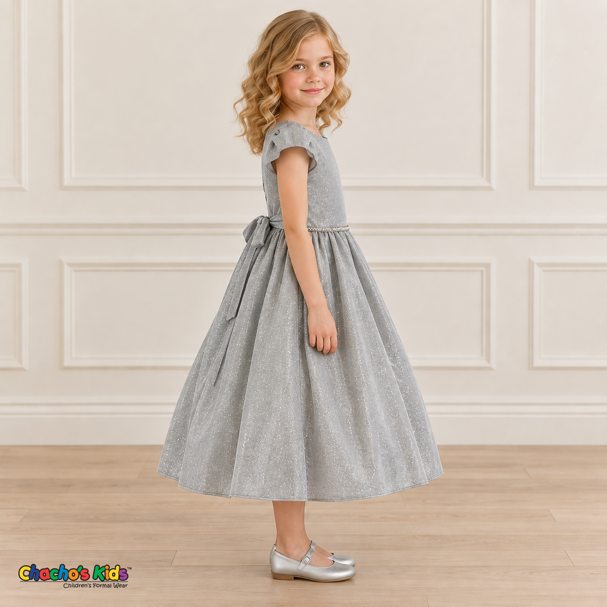 Side view of a girl wearing the silver shimmer puff sleeve party dress, Style 444, showing the gathered skirt and matching back sash.