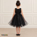 Back view of the black Style 9150 tulle dress on a girl, showing the zipper, matching satin bow, and layered curled hem.