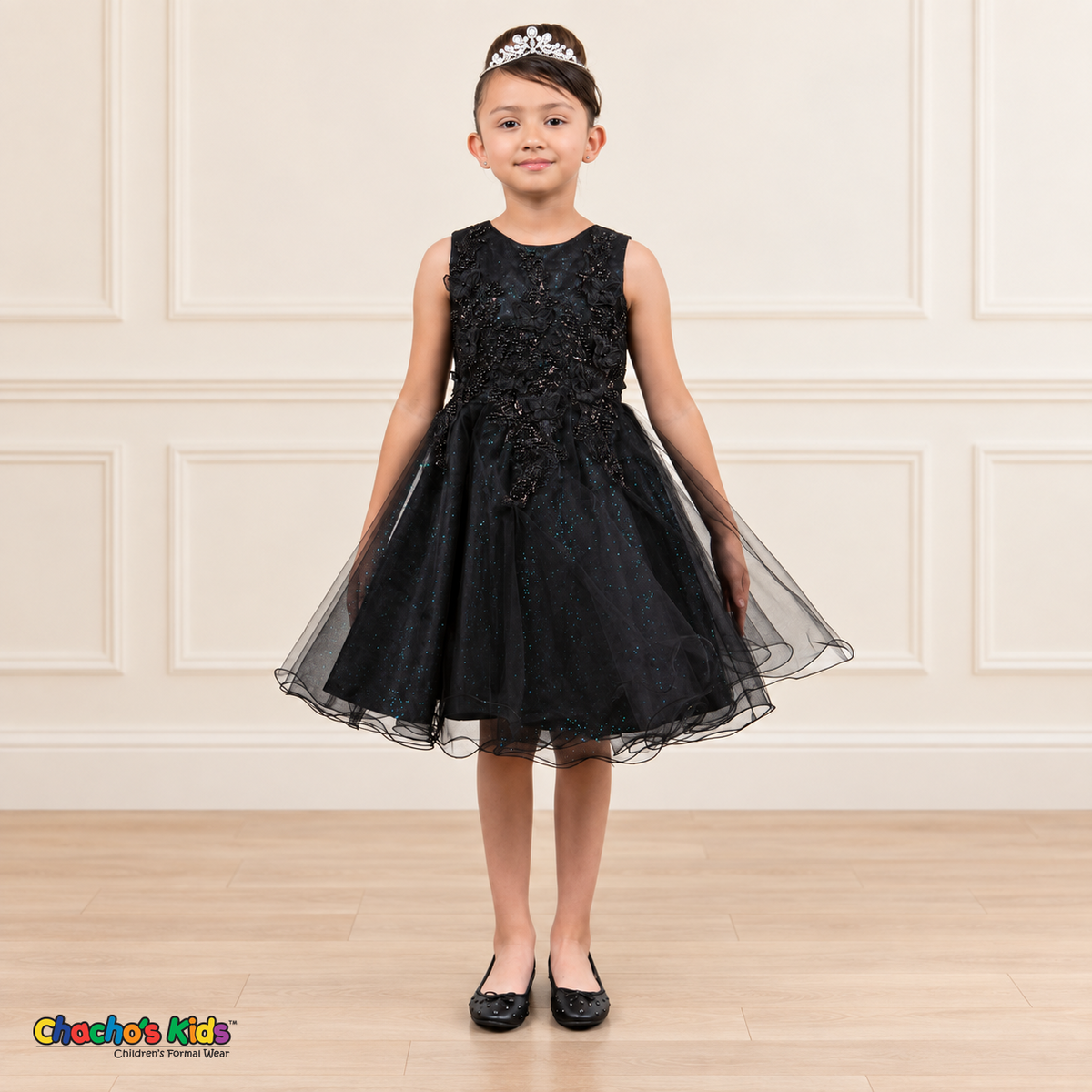 Front view of a girl wearing the black Style 9150 butterfly embroidered tulle dress with pearl accents and a curled hem.
