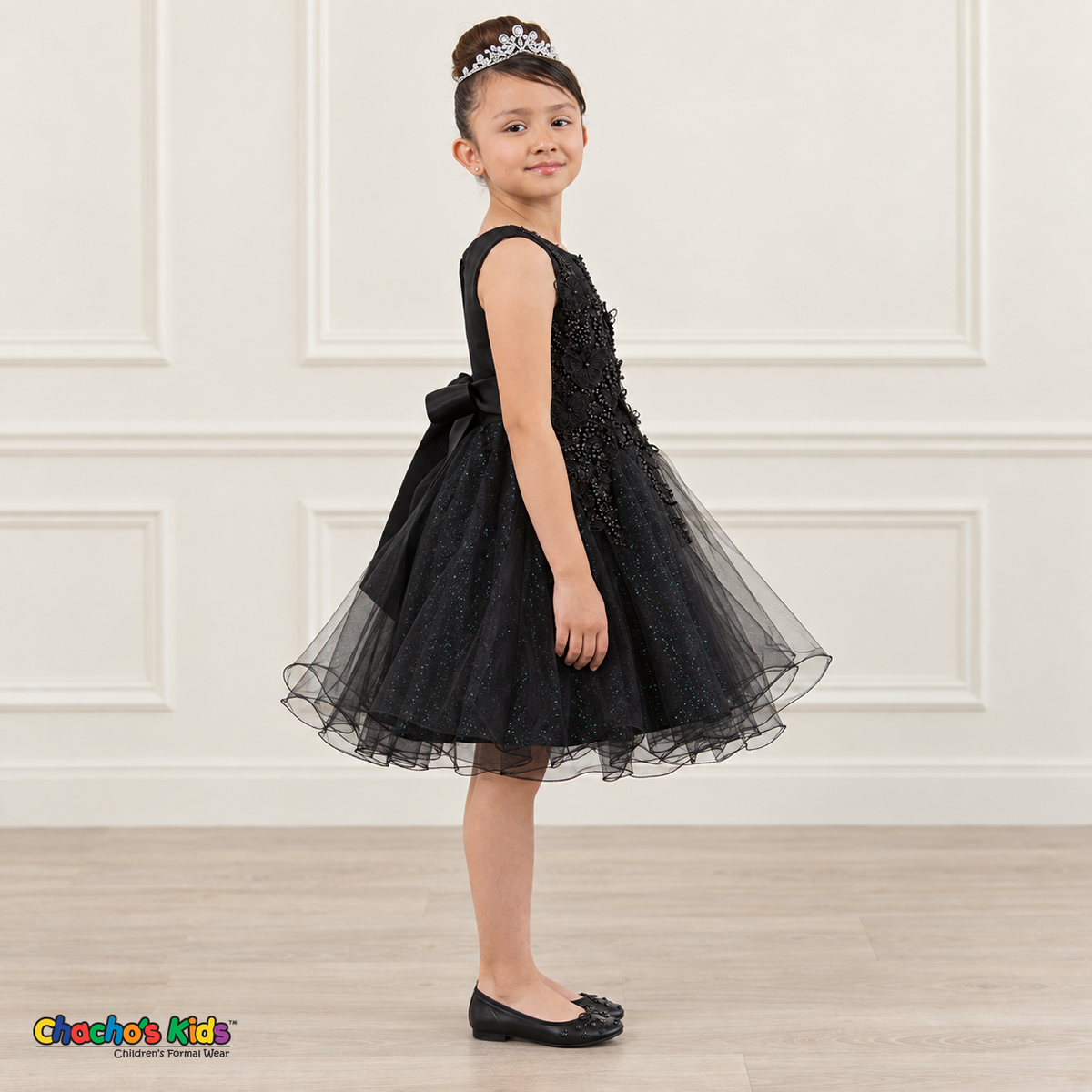 Side view of a girl wearing the black Style 9150 butterfly embroidered dress with a full layered tulle skirt.