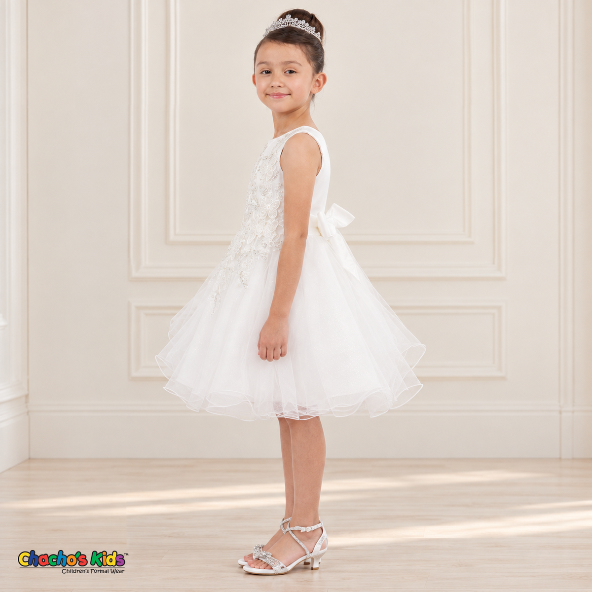 Side view of a girl wearing the white Style 9150 butterfly embroidered dress with a full layered tulle skirt.