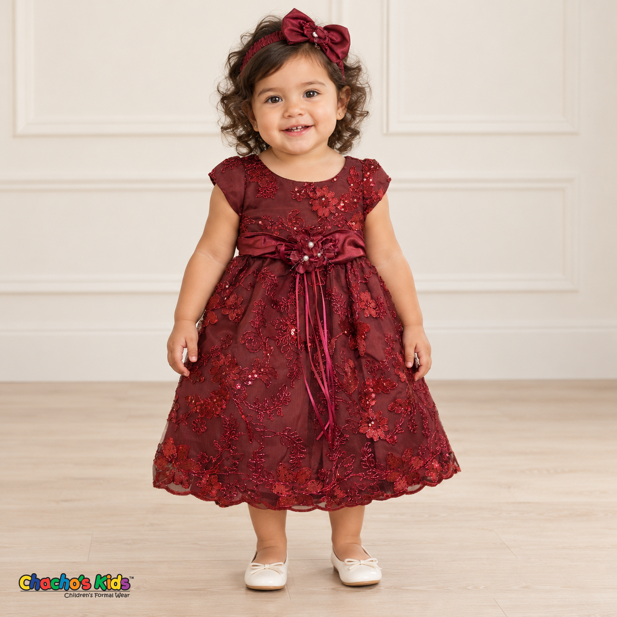 Baby girl wearing the Burgundy Baby Floral Rosette Dress D-1664, front view with matching bow headband.