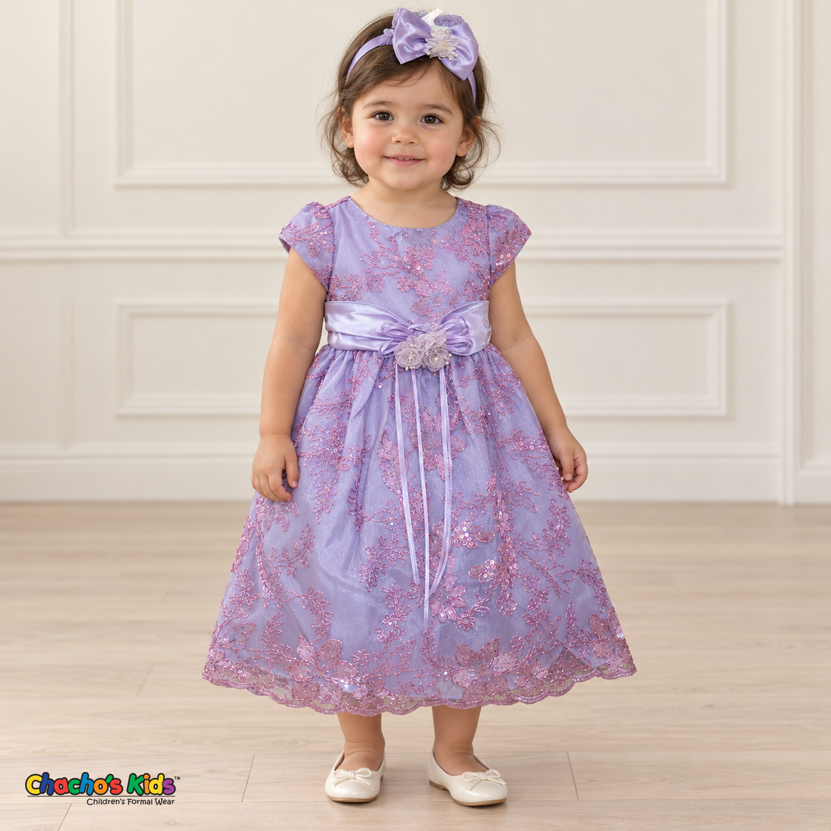 Baby girl wearing the Lilac Baby Floral Rosette Dress D-1664, front view with matching bow headband.