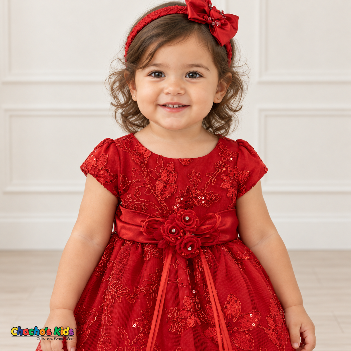 Baby girl wearing the Red Baby Floral Rosette Dress D-1664, floral waist sash and rosette detail.