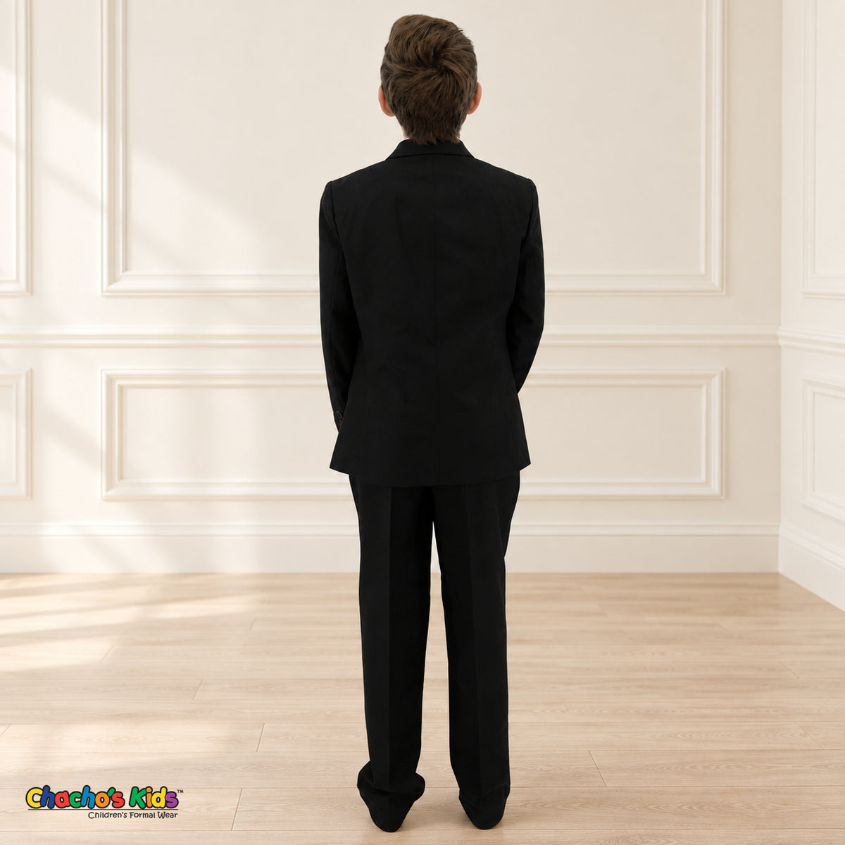 Black BJ4005 Executive boys suit on the existing child model, back view showing the coat silhouette and matching trousers.