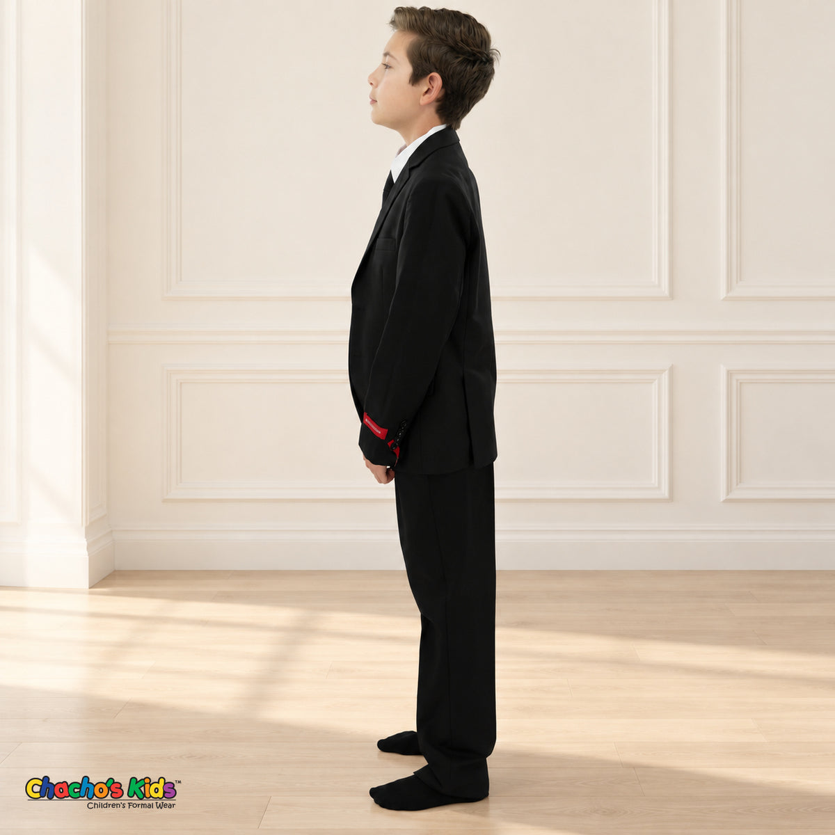 Black BJ4005 Executive boys suit on the existing child model, left side view showing the tailored coat and matching full-length trousers.