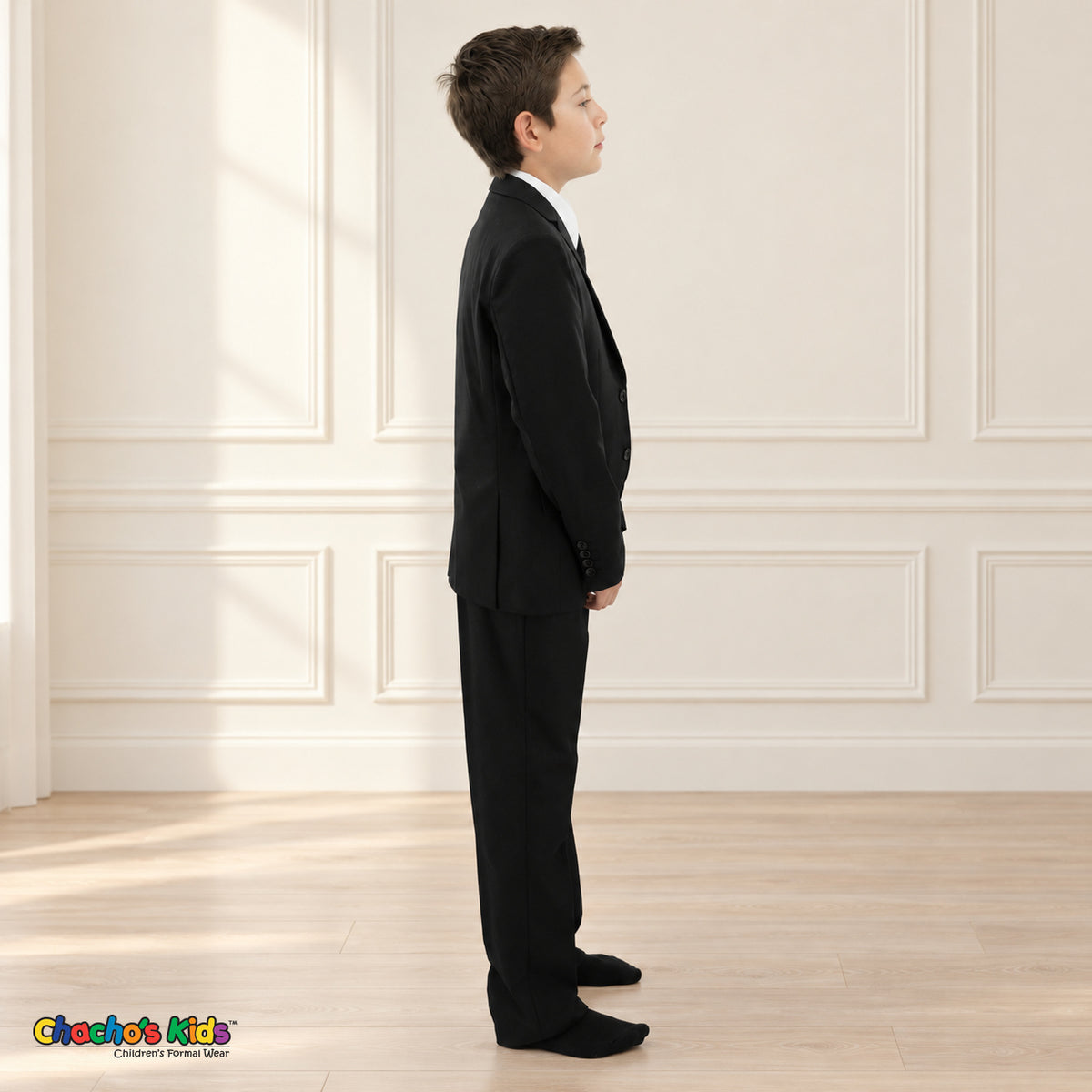 Black BJ4005 Executive boys suit on the existing child model, right side view showing the tailored coat, sleeve buttons and matching trousers.