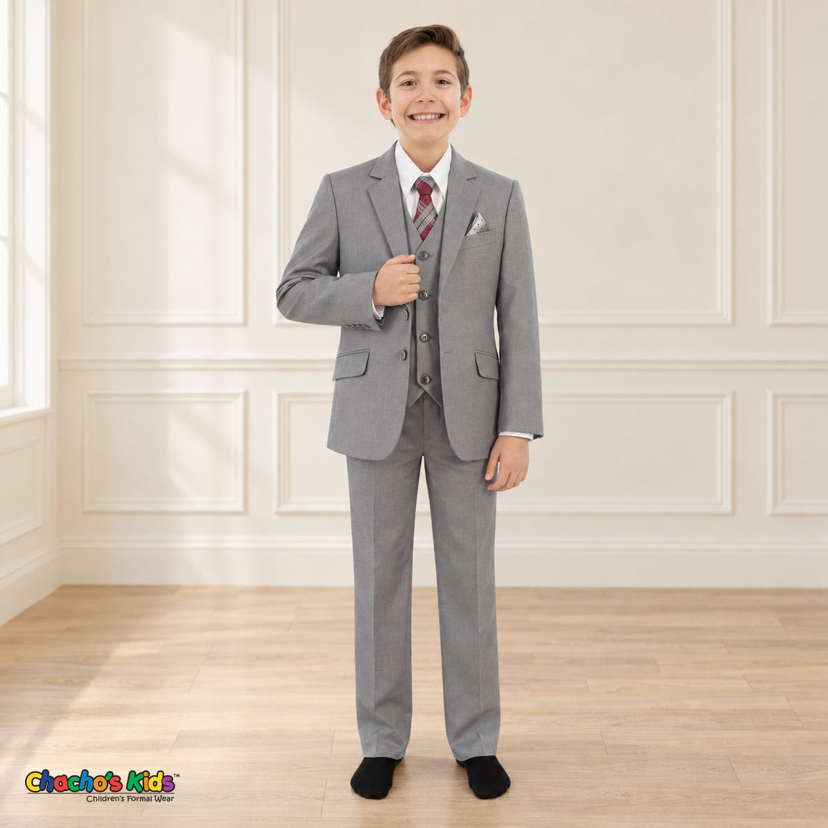 Gray BJ4005 Premium Executive boys suit on the existing child model, full front view with white shirt, patterned tie and coordinating dotted pocket square.