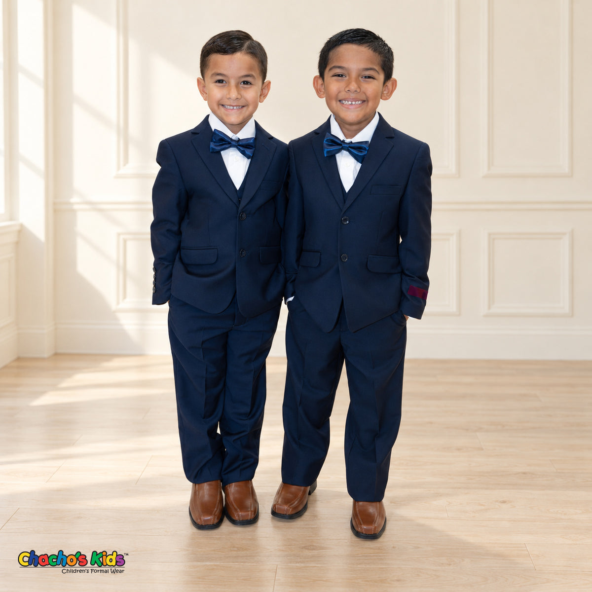 Two boys wearing navy blue BJ4005 suits with white shirts, blue satin bow ties and brown dress shoes.