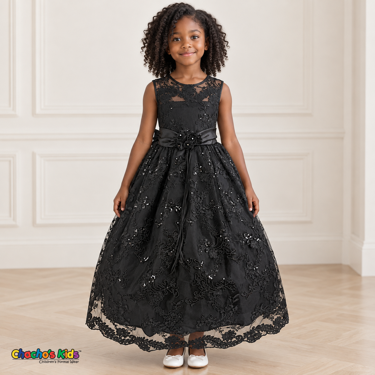 Girl wearing the Black Floral Embroidered Dress, Style D1550, front view, showing floral embroidery, sequins and a rosette waist accent.