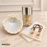 Boys baptism accessories: ivory-trimmed shell, gold-tone rosary in a silver-lid jar, brown-ribbon scapular, and delicate ivory handkerchief.