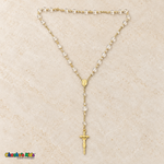 Clear-bead baptism rosary outside its jar with a gold-tone chain, devotional medallion, and crucifix.