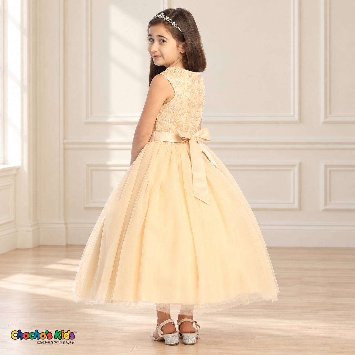 Champagne KE07 floral embroidered tulle dress on the same child model, rear three-quarter view showing the satin tie-back sash.