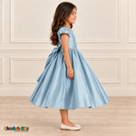 Side view of a girl wearing a pale light-blue satin party dress with short puff sleeves, a jeweled waist and a full skirt.