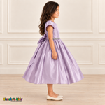Side view of a girl wearing a lilac satin party dress with short puff sleeves, a jeweled waist and a full skirt.