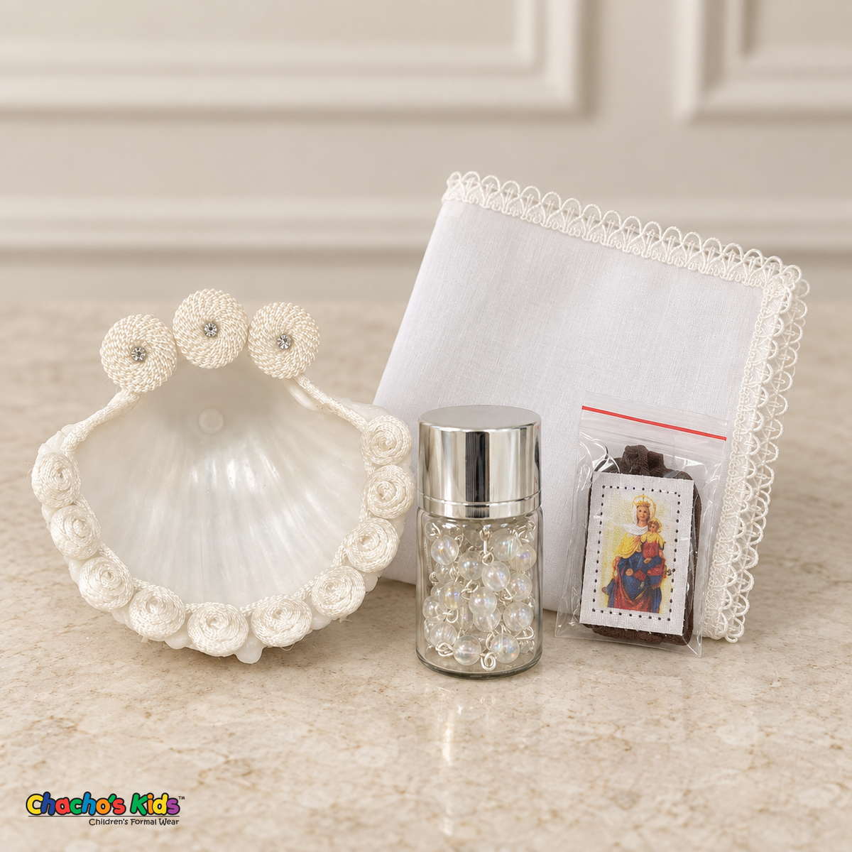 Baptism shell with cord rosettes, silver-lidded rosary jar, brown-ribbon scapular, and lace-edged handkerchief.
