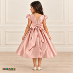 Back view of a girl wearing a soft pink satin party dress with a V-shaped neckline, zipper and large matching sash bow.