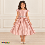 Girl wearing a soft pink satin party dress with short puff sleeves, a sparkling waist and a full gathered skirt.
