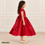 Side view of a girl wearing a red satin party dress with puff sleeves, a jeweled waist and a large back bow.
