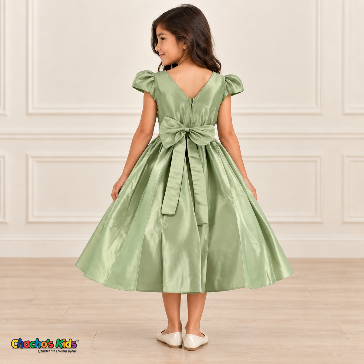 Back view of a girl wearing a sage green satin party dress with a V-shaped neckline, zipper and large matching satin bow.