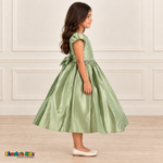 Side view of a girl wearing a sage green satin party dress with puff sleeves, a jeweled waist and a large back bow.