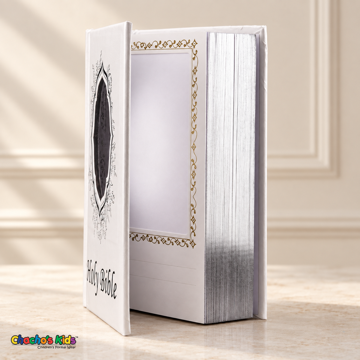 Open white English Holy Bible showing its inner photo pocket, gold scroll border and silver page edges.