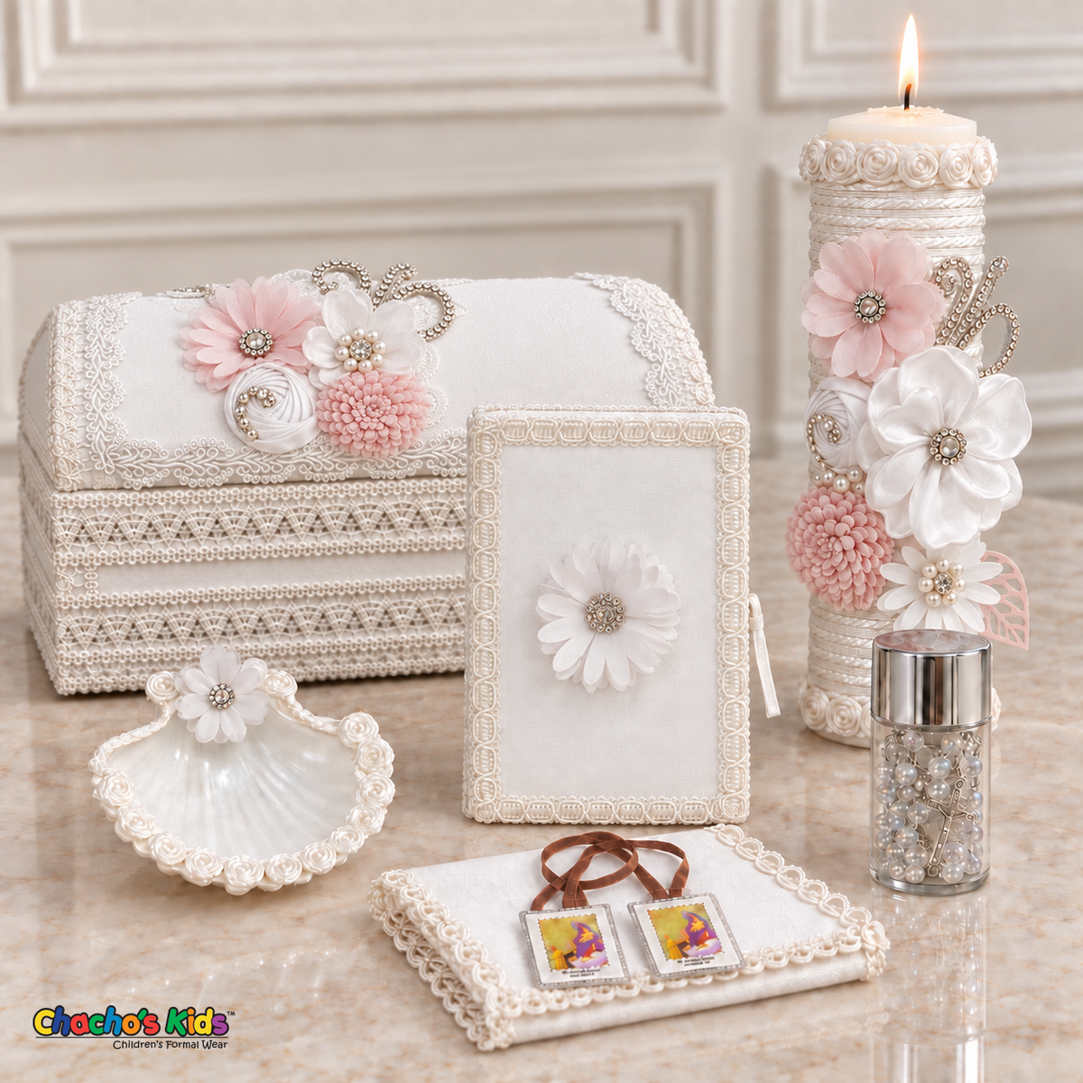 Seven-piece white floral baptism keepsake set with a long chest, lit candle, Bible, shell, rosary, handkerchief and visible scapular.