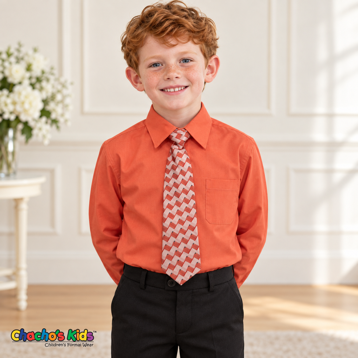 Boy wearing a classic melon long-sleeve dress shirt with its coordinating patterned tie and black dress pants