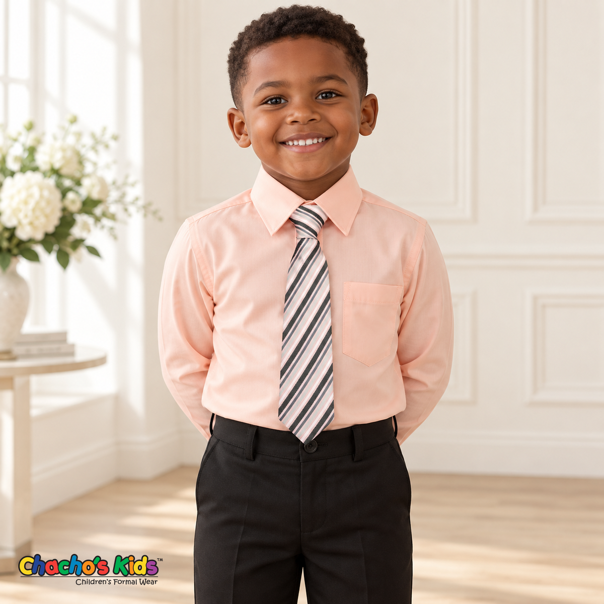 Boy wearing a classic pink long-sleeve dress shirt with its coordinating patterned tie and black dress pants