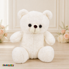 Front view of white Mini Quince teddy bear dress display in elegant cream interior with blush floral accents